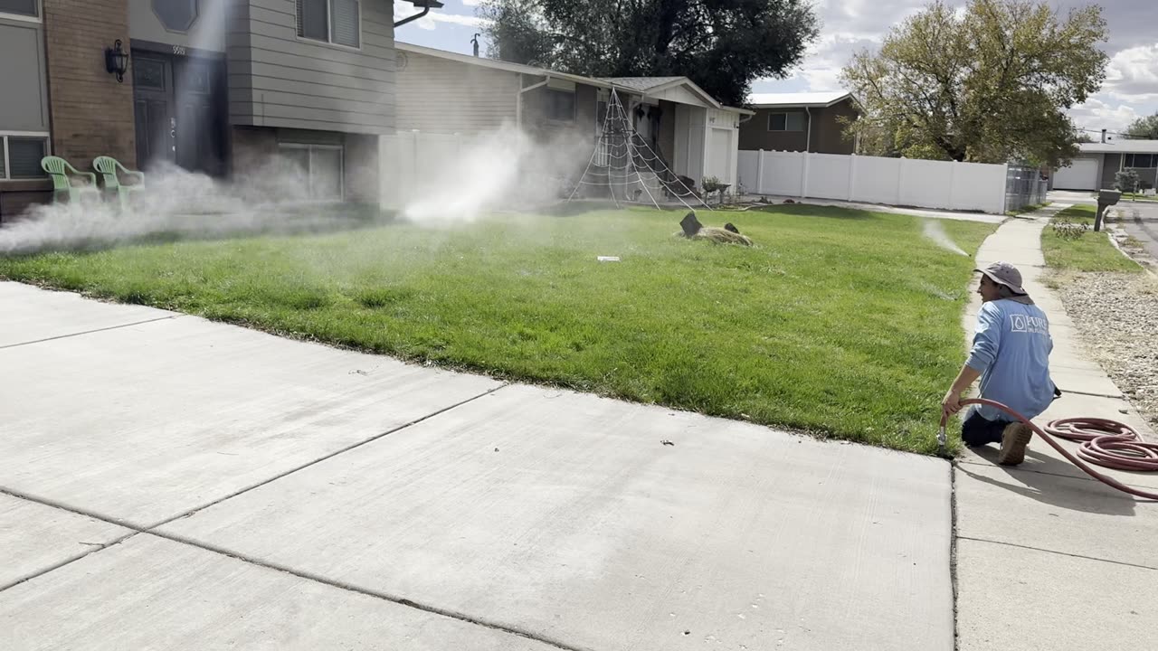 A Pure Irrigation technician blowing out a sprinkler system with compressed air