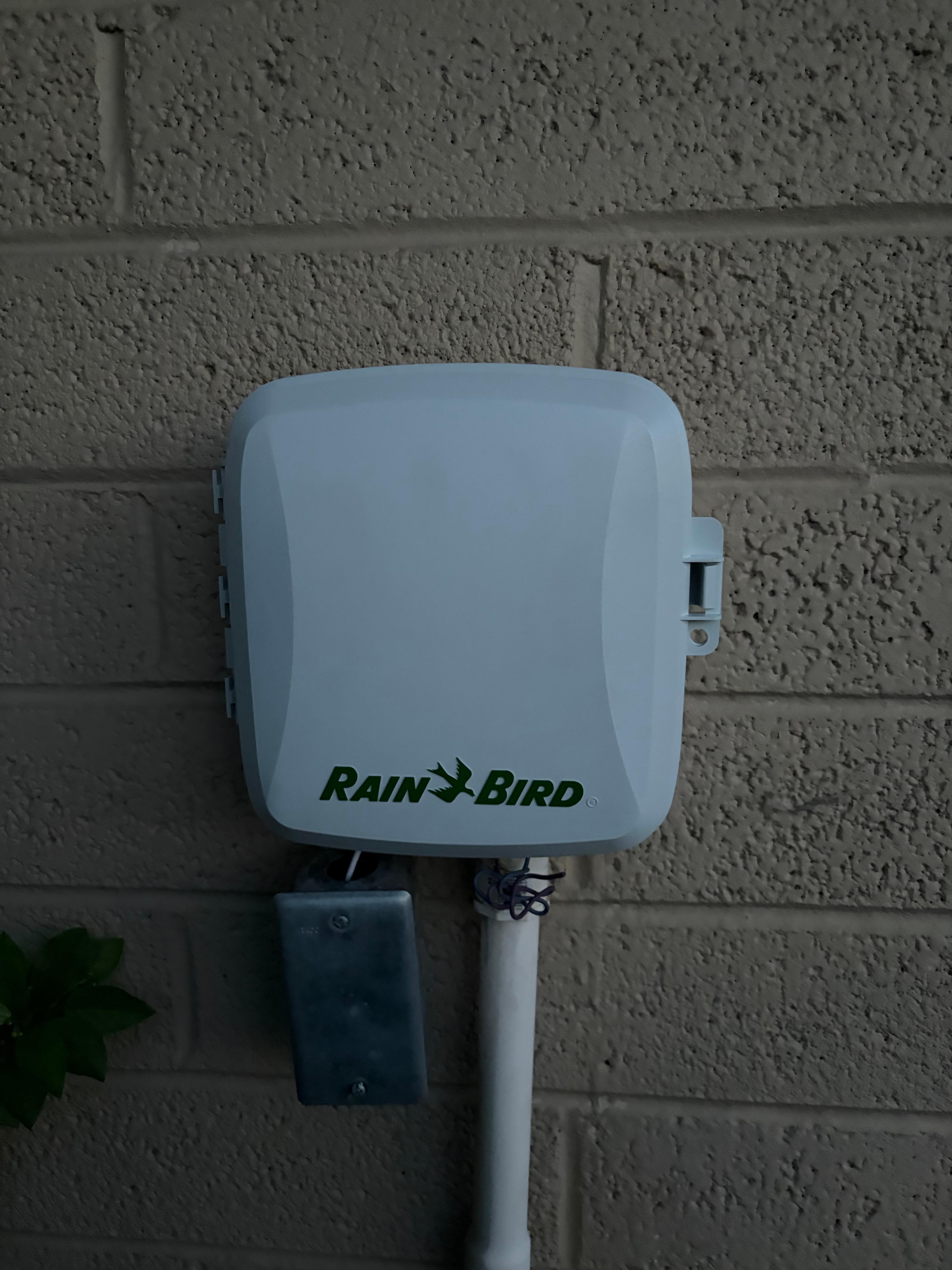 A Rain Bird sprinkler controller installed on an exterior wall